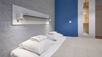 A hotel room with a patterned wall, a bed with white linens, and a blue accent wall.