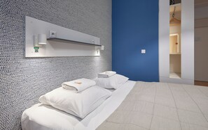 A hotel room with a patterned wall, a bed with white linens, and a blue accent wall. - Hotel Traffic Wrocław Stare Miasto (Wroclaw)