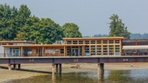 A modern building with a flat roof and large windows, situated near a body of water. - Direct Ocean Front Access/private entry I BDRM, full bathroom, all season patio. (Mill Bay)