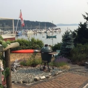 Un port de plaisance avec des bateaux amarrés, un drapeau et un barbecue dans un espace aménagé en jardin.