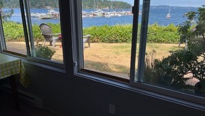 A room with large windows overlooking a marina with boats and greenery. - Direct Ocean Front Access/private entry I BDRM, full bathroom, all season patio. (Mill Bay)