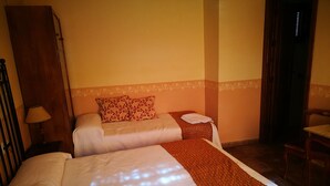 A hotel room with two beds, a wooden wardrobe, a small table with a lamp, and a chair. - Balcon del Velillos - Rincón de Marcelo (Moclin)