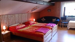 Une pièce chaleureuse avec un plafond en bois, un lit avec deux oreillers, une chaise et une petite table.