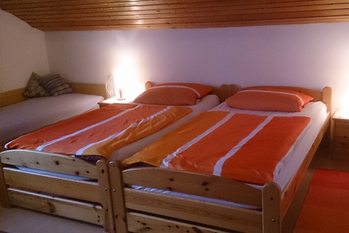Ein Doppelbett mit orange-weißen Streifen, zwei Nachttische mit Lampen und ein Holzkopfstück.