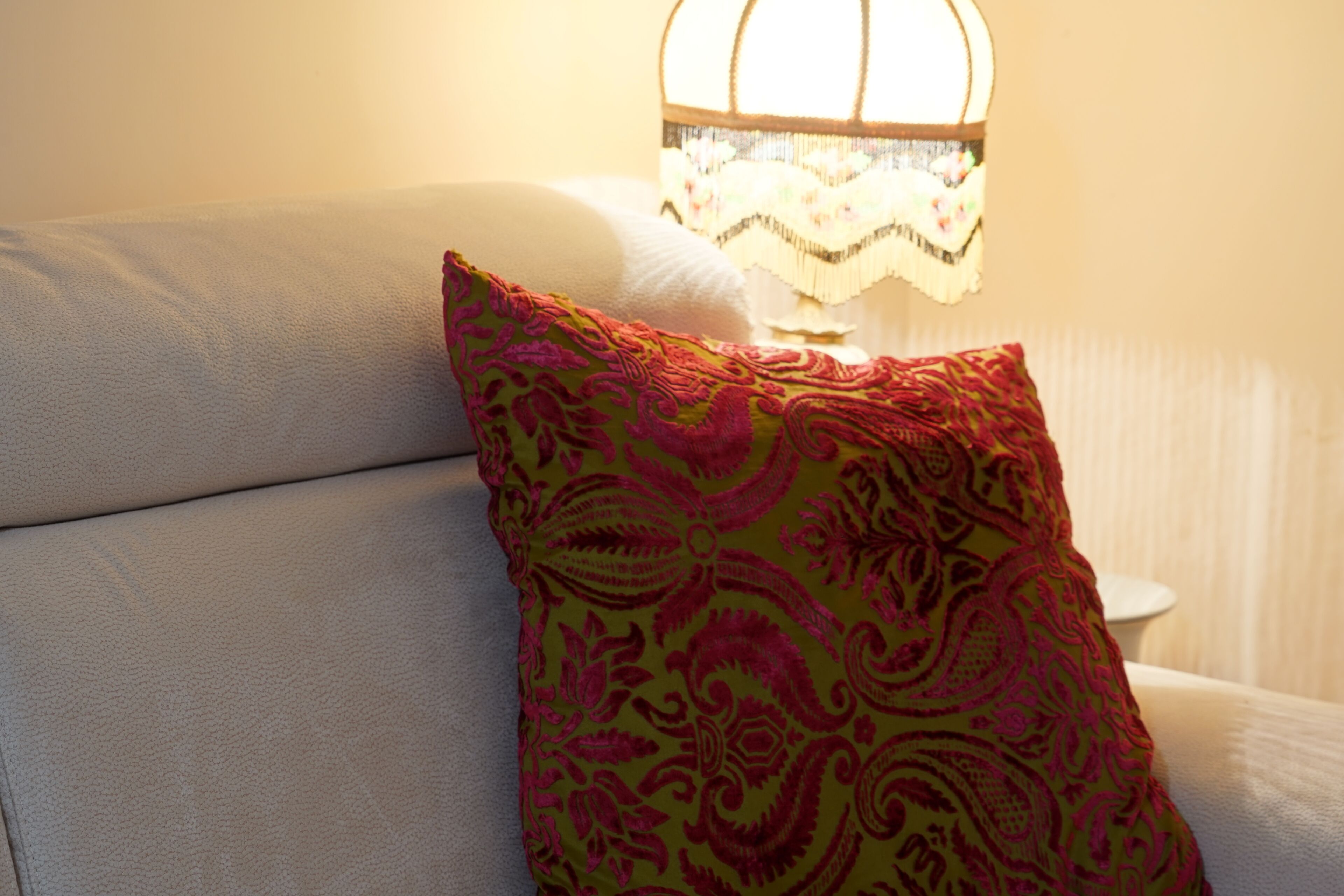 Un canapé agrémenté d’un coussin à motifs et d’une lampe fixée au mur.