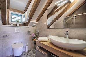 Een moderne badkamer met een houten plafond, een groot wastafel en een toilet.