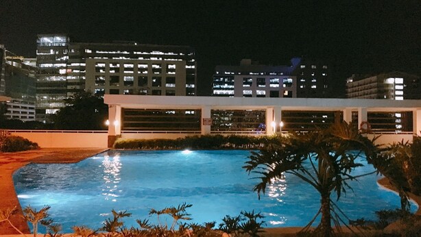 Una piscina con vistas a un paisaje urbano nocturno.