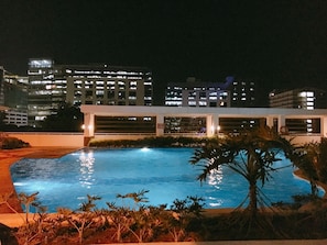 A swimming pool with a view of a cityscape at night.