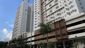 Un edificio residencial alto con varios balcones y una estructura de aparcamiento abajo.