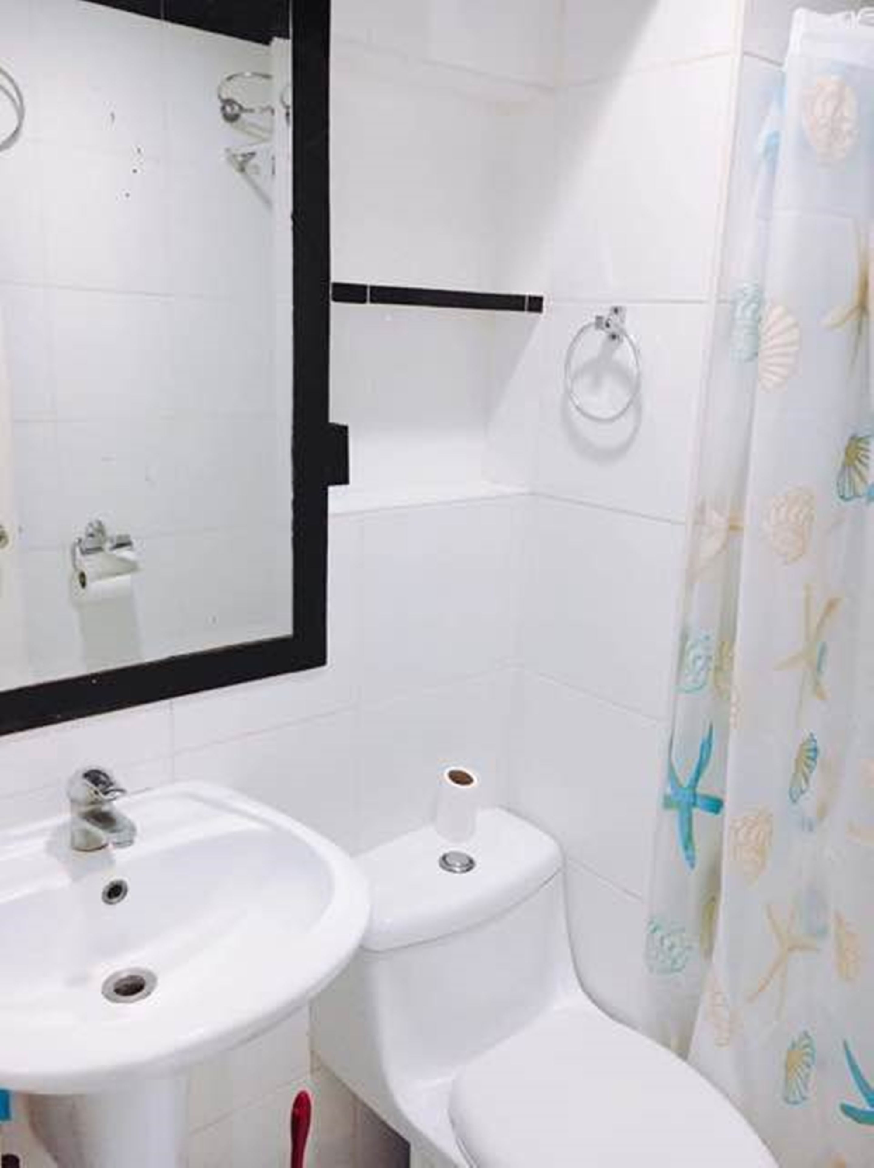 Un baño con lavamanos, inodoro y espejo blancos.
