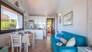 A compact living space with a dining area, a kitchen, and a blue sofa.