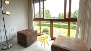 A room with a large window, a round table with four yellow bowls, two brown ottomans, and a floor lamp. - My Home - Copenhague (Gramado)