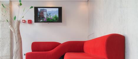 Una sala de estar moderna con un sofá seccional rojo, un adorno de madera y un televisor montado en la pared.