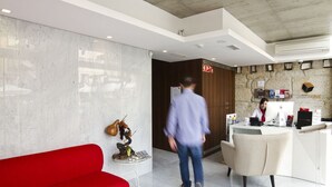 A hotel reception area with a marble wall, a red sofa, a reception desk, and a statue. - Oca Ribeira do Porto Hotel (Porto)