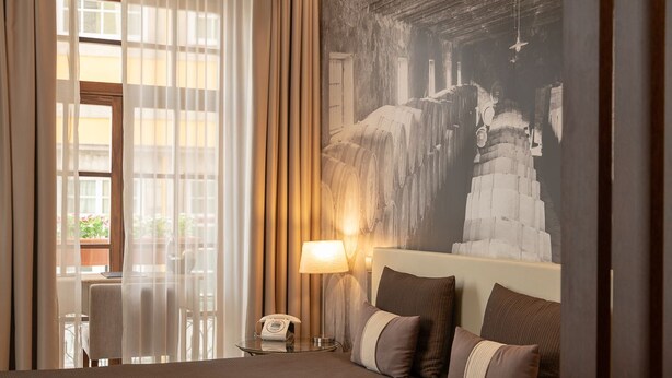 A hotel room with a bed, a nightstand with a lamp, a telephone, and a large wall mural. - Oca Ribeira do Porto Hotel (Porto)
