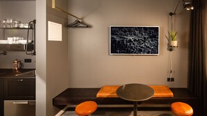 A modern kitchen with a built-in oven, a dining area with a round table and orange seating, and a wall-mounted plant. - Urban Reykjavik Studios (Reykjavik)