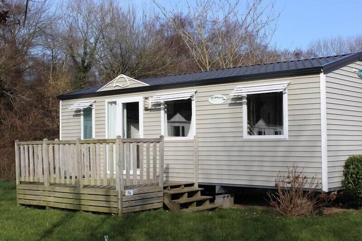 A small, single-story mobile home with a front porch and a deck.