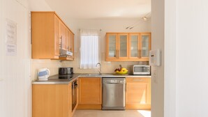 A compact kitchen with wooden cabinets, a dishwasher, a microwave, and a fruit bowl. - Beautiful holiday house with Heated Pool, Private Patio and Great Location (Puerto del Carmen)