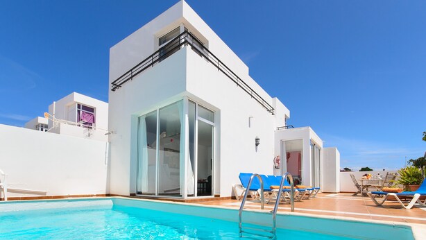 A modern building with a swimming pool, sun loungers, and a clear blue sky. - Beautiful holiday house with Heated Pool, Private Patio and Great Location (Puerto del Carmen)