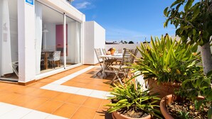 A patio with a table and chairs, potted plants, and a building entrance. - Beautiful holiday house with Heated Pool, Private Patio and Great Location (Puerto del Carmen)