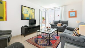 A living room with a sofa, a coffee table, a TV, and a painting on the wall. - Beautiful holiday house with Heated Pool, Private Patio and Great Location (Puerto del Carmen)
