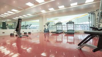 A gym with exercise equipment, a red floor, and large windows.
