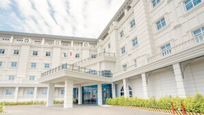 A large, white building with multiple floors and a central entrance. - The Monarch Hotel (Calasiao)