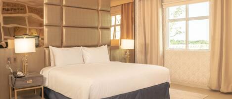 A large bed with a headboard, bedside lamps, and a nightstand with a phone.