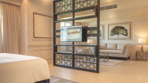 A hotel room with a bed, a sofa, a TV, and a decorative screen. - The Monarch Hotel (Calasiao)