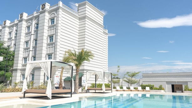A hotel with a large pool, outdoor seating, and a traditional architectural style. - The Monarch Hotel (Calasiao)