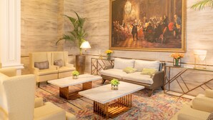 A spacious lobby with a large classical painting, comfortable seating, and a decorative chandelier. - The Monarch Hotel (Calasiao)