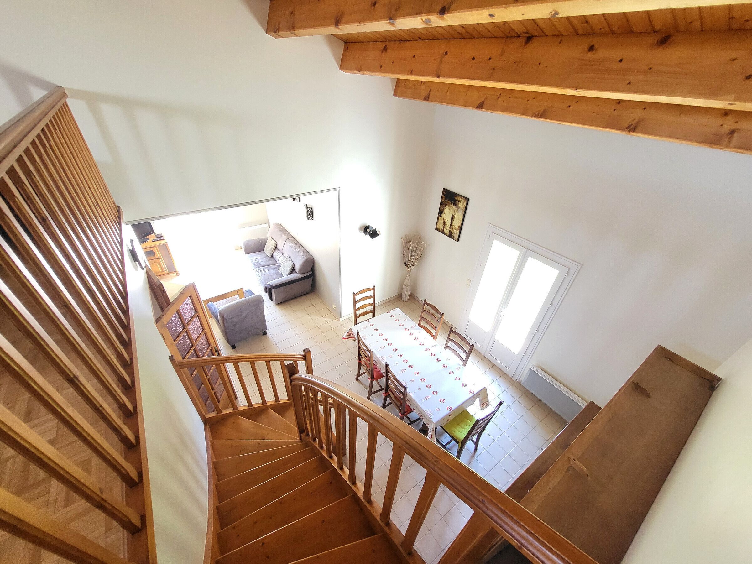 Un escalier menant à un espace repas comprenant une table et des chaises, un canapé et une fenêtre.