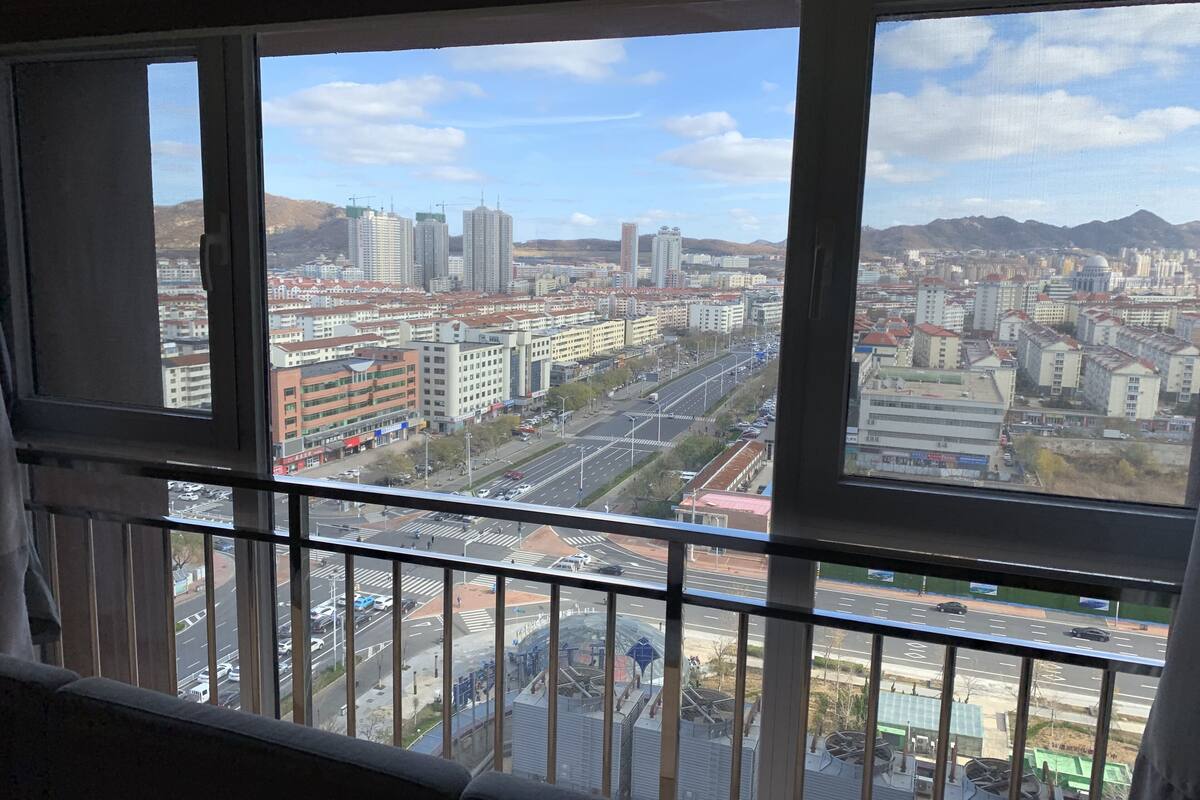 A cityscape through a window with a view of buildings, roads, and a distant mountain range.