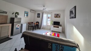 Un espace de vie compact comprenant un coin cuisine, un coin repas, un téléviseur et un lit.