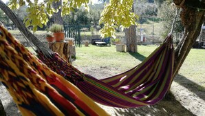 A hammock hanging between trees in a garden with potted plants and a fence in the background. - Baduerughe (Poggio Mirteto)