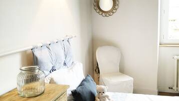 Un dormitorio con cama, mesita de noche, lámpara y espejos decorativos.