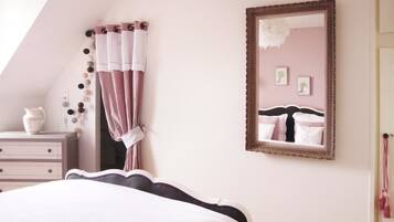 A bedroom with a bed, a dresser, a mirror, and a wall with a picture frame.