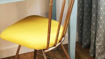 Una silla con un cojín amarillo y estructura de bambú, ubicada frente a una mesa oscura.