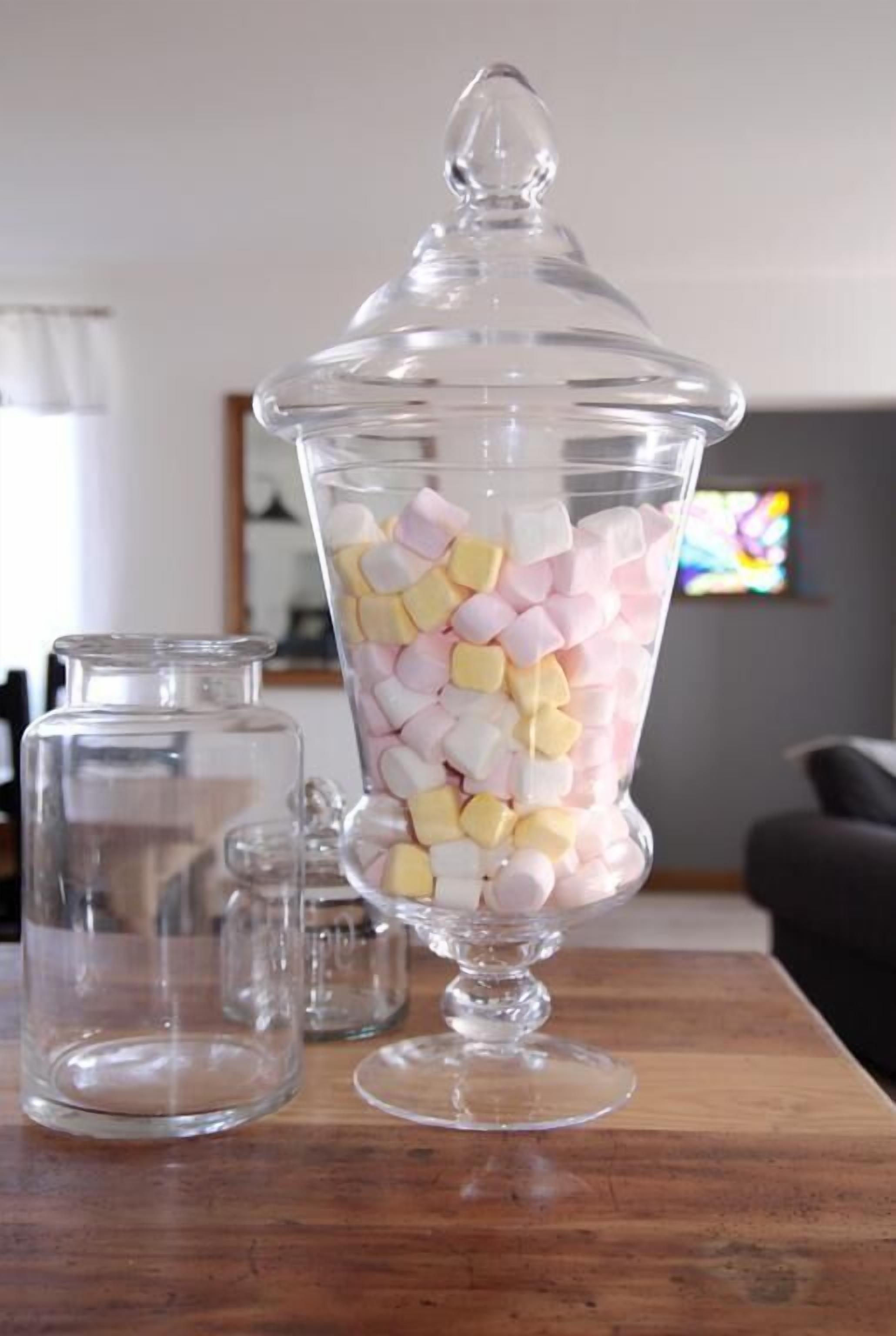 Een glazen pot gevuld met kleurrijke marshmallows op een houten tafel.