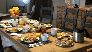 A breakfast table set with various dishes, including fruits, bread, and beverages. - Il Etait Une Fois à L'Ouest (Plestan)