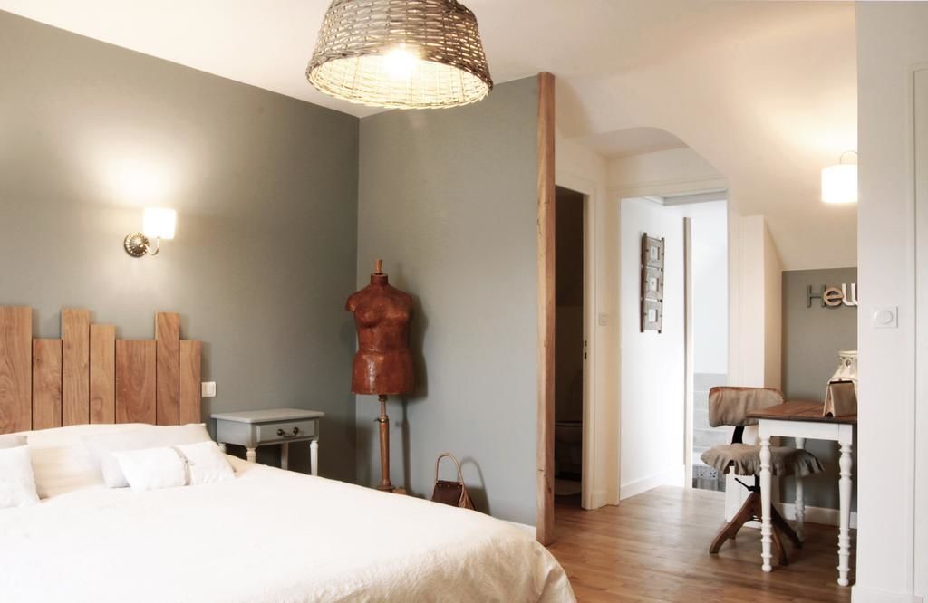 Une chambre à coucher avec un lit, une tête de lit en bois, un mannequin et un bureau avec une chaise.