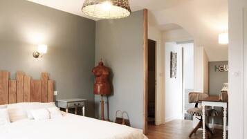Een slaapkamer met een bed, een houten hoofdbord, een etalagepop en een bureau met een stoel.