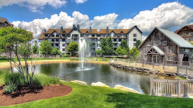 A hotel with a pond, a wooden bridge, and a fountain. - 1st Fl Condo 3BR @ Stratton Sleeps 7 Pool Hot Tub (Stratton Mountain)