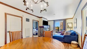 A dining area with a wooden table and chairs, a blue sofa, and a chandelier. - 1st Fl Condo 3BR @ Stratton Sleeps 7 Pool Hot Tub (Stratton Mountain)