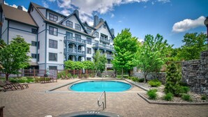 A hotel with a swimming pool, outdoor seating, and a stone wall. - 1st Fl Condo 3BR @ Stratton Sleeps 7 Pool Hot Tub (Stratton Mountain)
