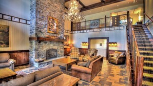 A spacious lobby with a stone fireplace, comfortable seating, and a staircase leading to an upper level. - 1st Fl Condo 3BR @ Stratton Sleeps 7 Pool Hot Tub (Stratton Mountain)
