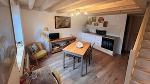 A cozy kitchen with wooden beams, a dining table, and a TV. - Gîtes du Fort (Collonges)