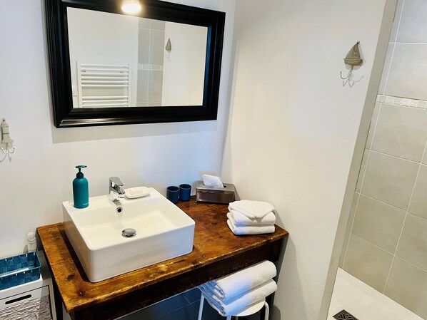 A bathroom with a white sink, a wooden countertop, a mirror, and a towel rack.