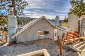 Situated on a quiet driveway, this charming building features a gabled roof and a chimney, surrounded by trees and a forested hillside.