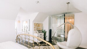 A bedroom with a bed, a hanging chair, a dresser, and a mirror. - Designer Historic Duplex Minutes from Downtown (Phoenix)